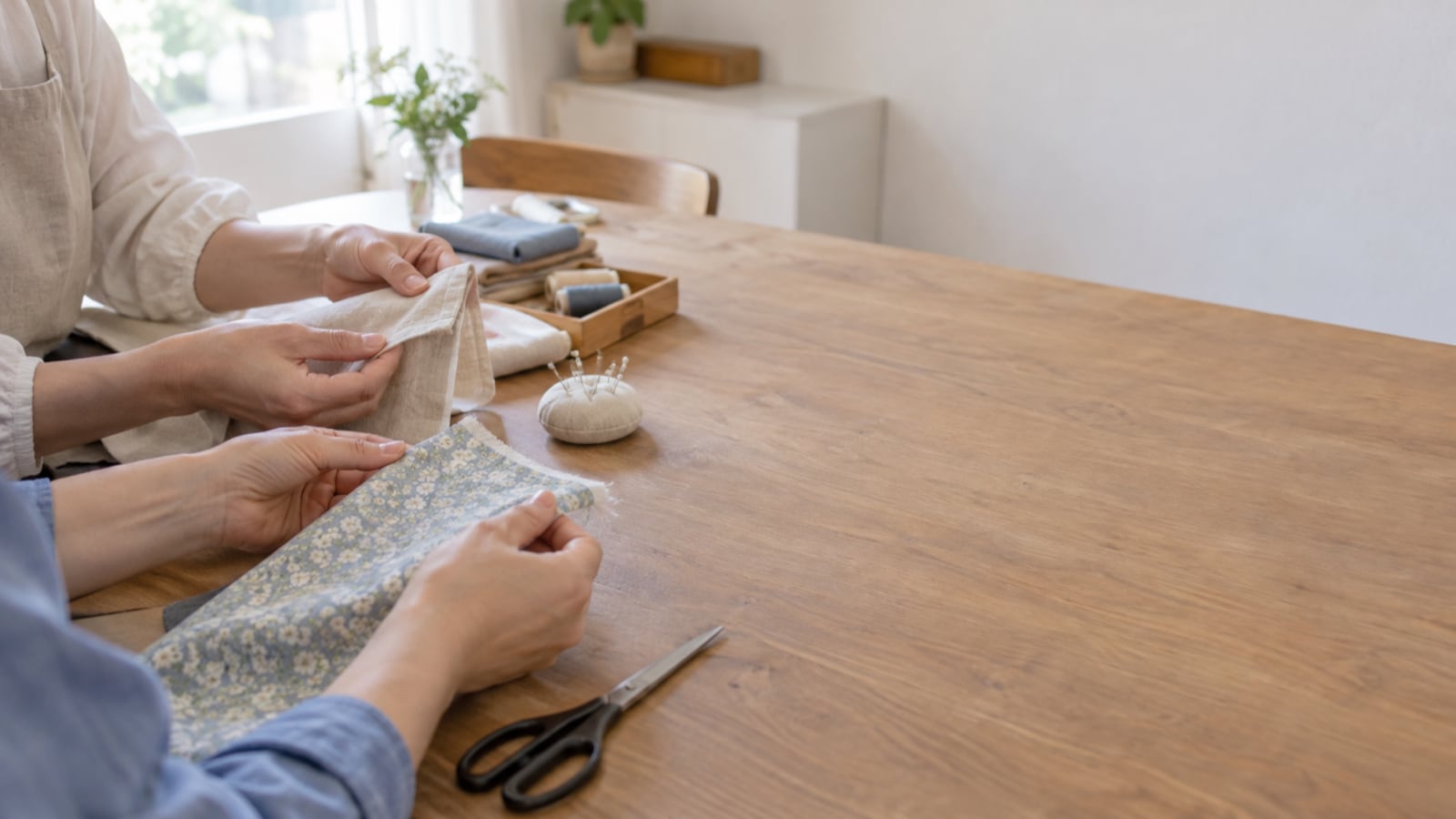 地域の手芸教室で二人が布の端を比べる手元